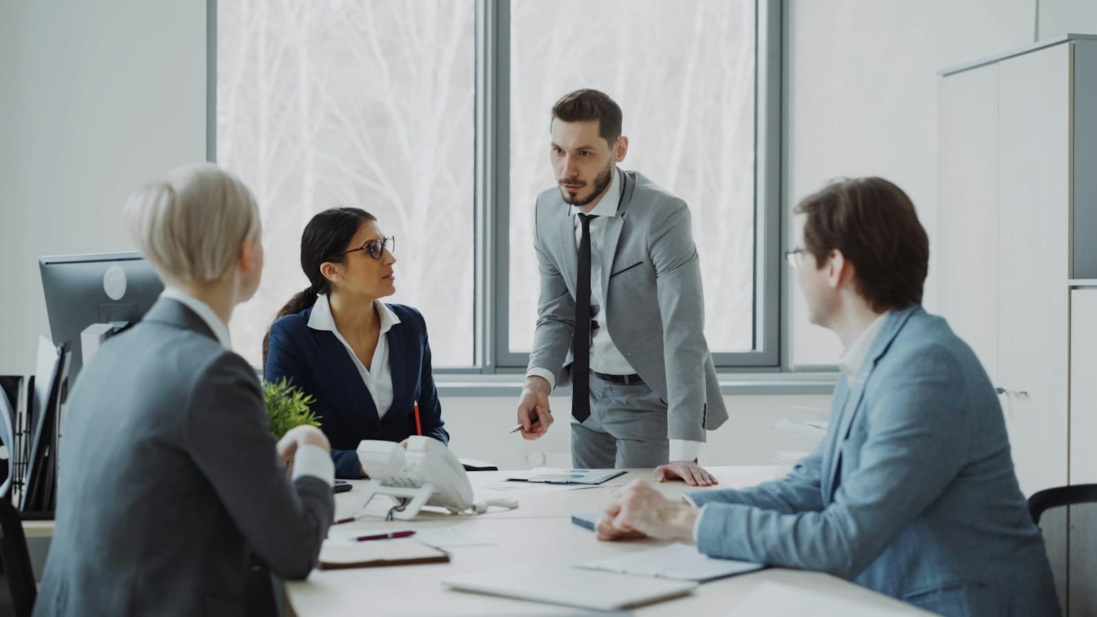 Four professionals in discussion around a boardroom table