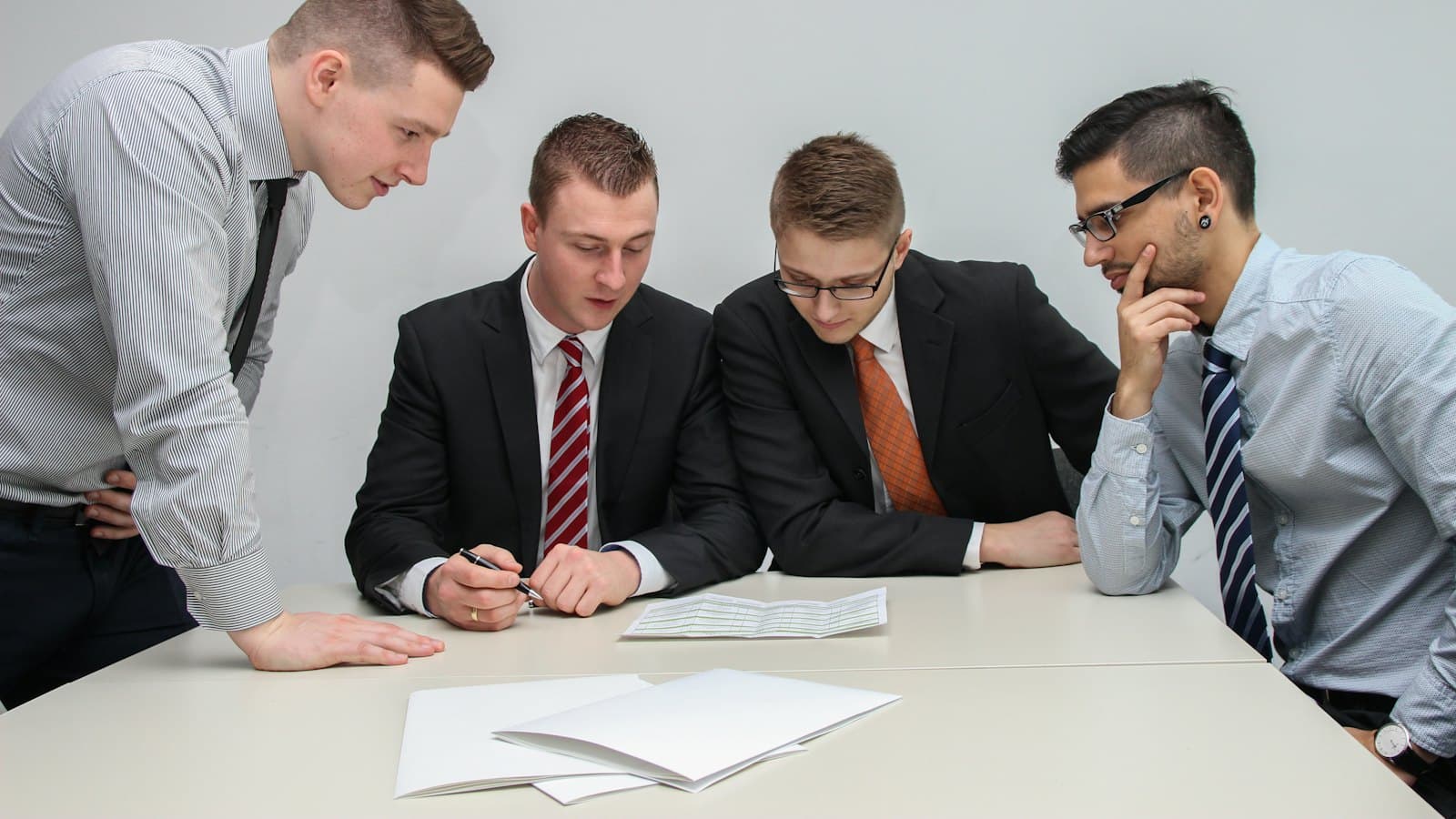 Four people in suits reviewing a document together at a table