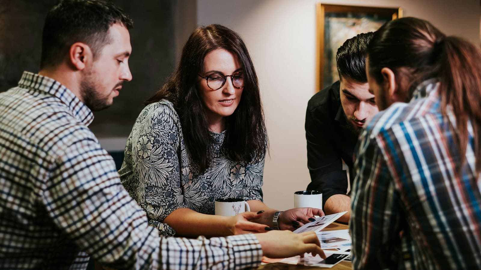 Four people reviewing documents together at a wooden table